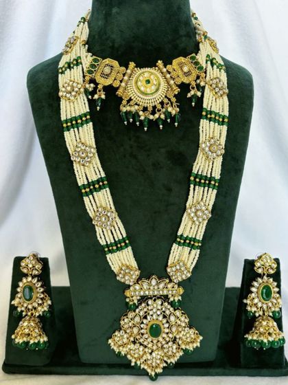 A grand Rani Haar made with multiple strands of pearls and green beads, featuring Kundan motifs. This rental set comes with a matching choker and earrings.