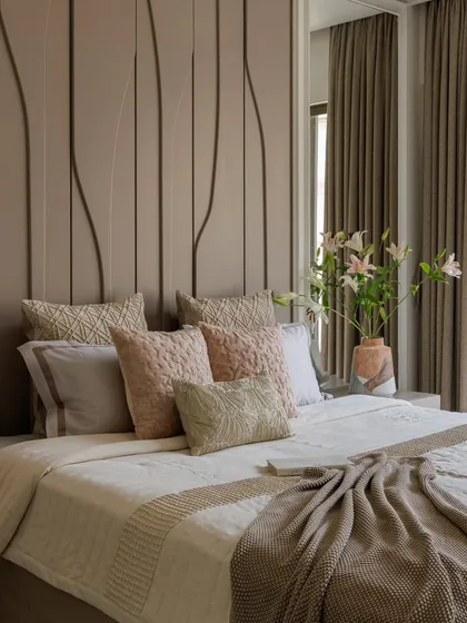 A close-up of the bed in our Santacruz apartment project. The layered textures of the pillows and the soft, neutral bedding create a sense of comfort and calm. The headboard's 3D texture adds a subtle design element.