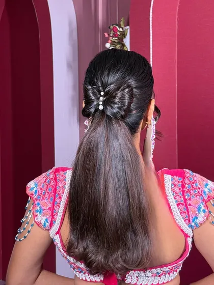 For a fun and glamorous Sangeet or cocktail party, I love creating chic styles like this sleek Barbie-inspired ponytail, finished with a delicate bow made of hair and pearls.