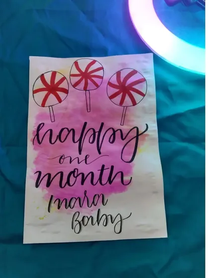 A sweet card for a baby's one month milestone, with a pink watercolor background and lollipop illustrations.