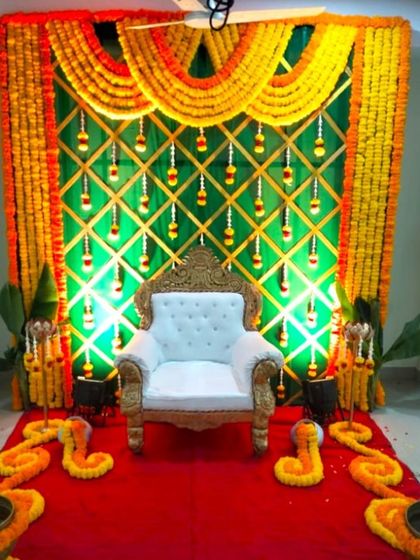 A traditional baby shower stage with a marigold and banana leaf backdrop. The setup includes a white throne for the mother-to-be and is lit for effect.
