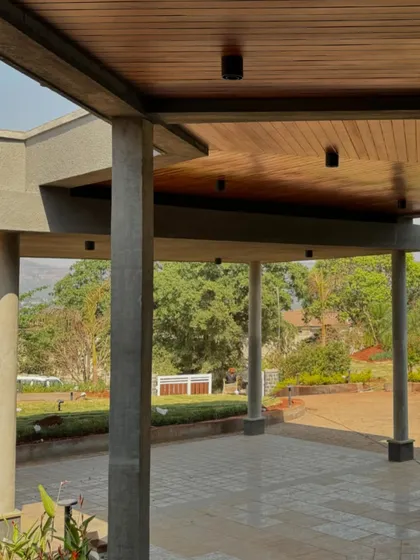 The covered verandah of the 6AM House. The concrete pillars and wooden ceiling create a sheltered outdoor space that feels like a natural extension of the interior living areas.