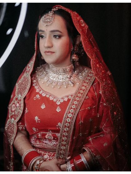 A classic portrait of the bride, Shreya, in her traditional red lehenga, her expression calm and poised.