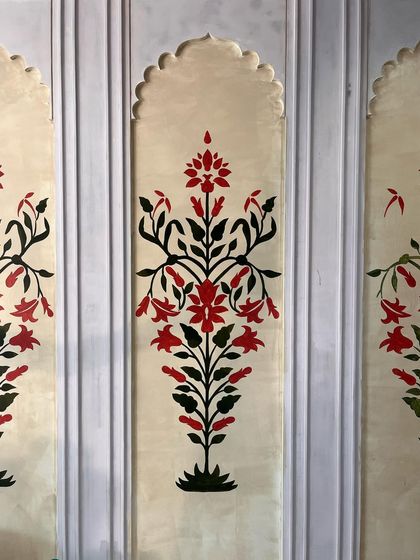 A close-up of the finished Mughal-style floral motif. The bold red and black design stands out against the textured, aged background, giving it a timeless feel.