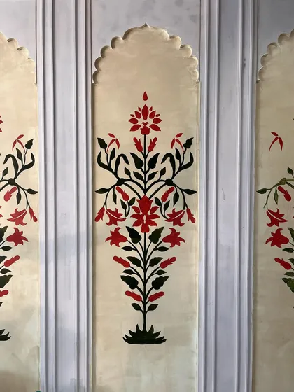 A close-up of the hand-painted Mughal floral panels, showcasing the symmetrical design and the classic red and black color palette.