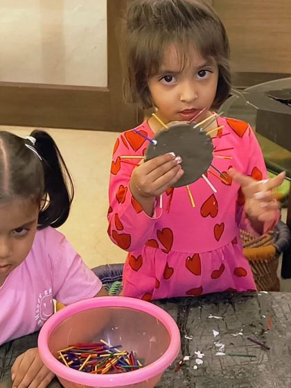 Two toddlers deeply focused on their summer clay activity. Working with clay is a fantastic sensory experience for developing fine motor skills.