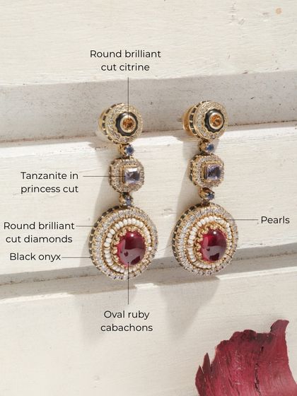 A detailed product shot of the Crimson Royal earrings, breaking down the symphony of gems: oval ruby cabochons, tanzanite, citrine, pearls, and diamonds.