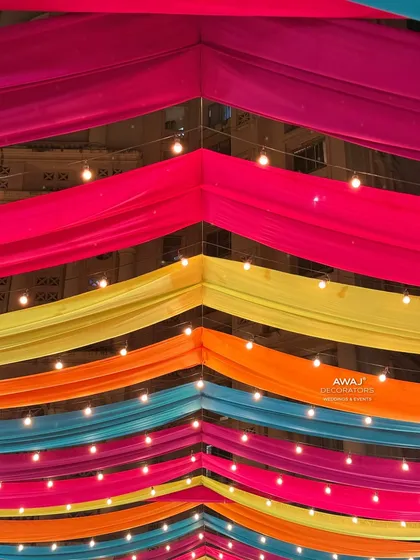 Looking up at the colorful draped ceiling, interspersed with strings of lights for a magical evening glow.