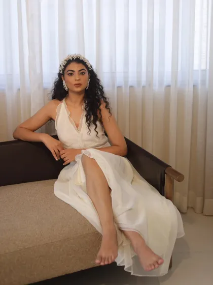 An elegant, soft-glam look for a fashion shoot. I focused on creating luminous skin, defined eyes, and styled the model's natural curls to complement the ethereal vibe of the white dress and accessories.