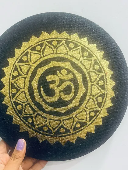 The sacred Om symbol, a sound that connects all of creation, painted in gold on a round black canvas. This minimalist yet powerful piece is perfect for a meditation space or as a symbol of peace in your home.
