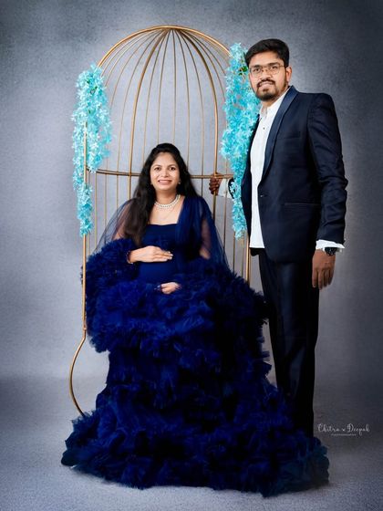 A formal portrait in shades of blue. The couple looks sharp and sophisticated next to the golden birdcage prop.