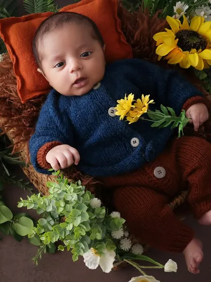 A fleeting moment of open eyes. Capturing a newborn when they are awake is a special treat. This little one looks curious and calm, holding a flower in our sunflower-themed setup.