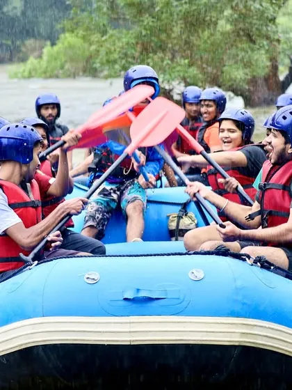 High-fives with paddles after successfully navigating a rapid. This moment of celebration shows the great teamwork and fun that defines our rafting courses in Coorg.
