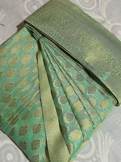 A light green saree with gold buttas, folded to keep it looking fresh.