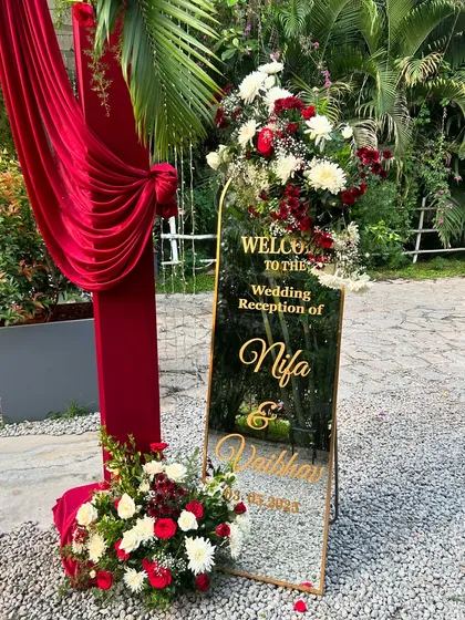Personalized details make all the difference. This elegant mirror welcome sign, adorned with classic red and white florals, greeted guests at a wedding reception, adding a personal and sophisticated touch to the entrance.