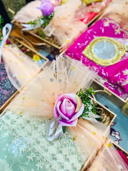 Beautifully decorated sagan favours for a wedding. Each gift box is wrapped in delicate peach and mint green net fabric with gold polka dots, and finished with a small rose and ribbon, creating a pretty and traditional party favour.