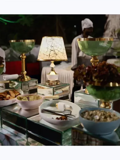 An elegant salad and appetizer bar with glass and gold serveware. The table lamps add a warm, inviting glow to the display.