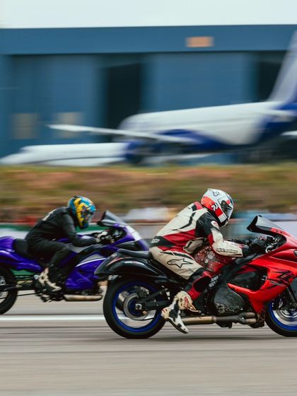 A neck-and-neck superbike race captured in a motion blur shot. Two riders push their machines to the absolute limit, fighting for every inch of the track.