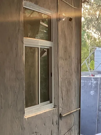 An outdoor camera placed near a window on a concrete wall. This helps monitor potential break-in points.
