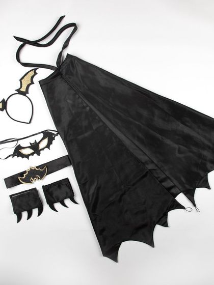A flat lay of a bat-themed costume, including a cape, mask, headband, and cuffs.