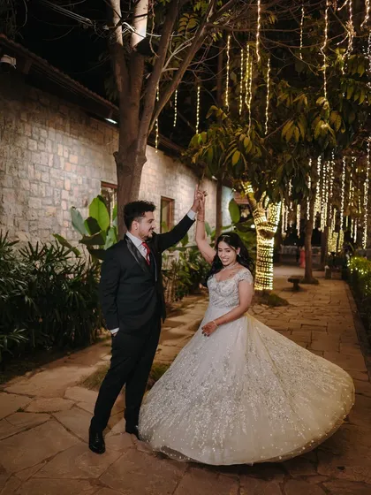 A fairytale moment for Pooja and Anirudh. The bride's stunning gown and the romantic dance under the fairy lights create a magical reception photo.