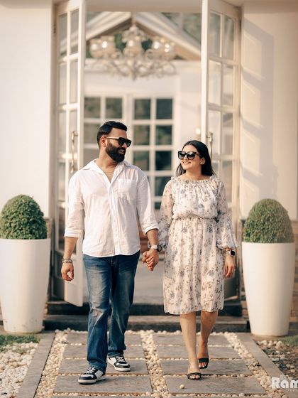 A happy, sun-kissed shot of a couple walking hand-in-hand. Their casual outfits and genuine smiles create a relaxed and joyful atmosphere for their outdoor pre-wedding shoot.