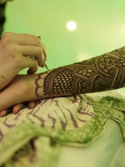 A work-in-progress shot showing the focus and precision that goes into every line of a bridal mehndi design.