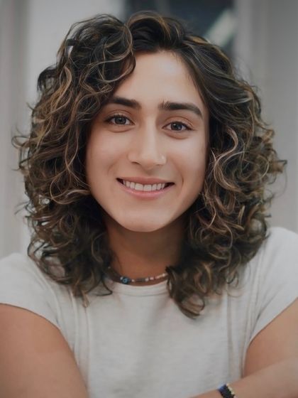 A smiling portrait of our client, showcasing his healthy, defined curls and a cut that perfectly suits his face shape.