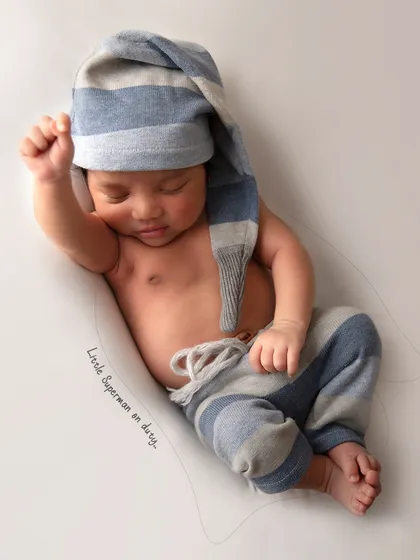 This little one looks like a superhero taking a nap. The simple, clean background keeps all the focus on the baby's adorable pose and outfit.