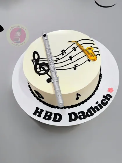 A minimalist black and white cake with a musical theme, featuring a fondant flute and saxophone.