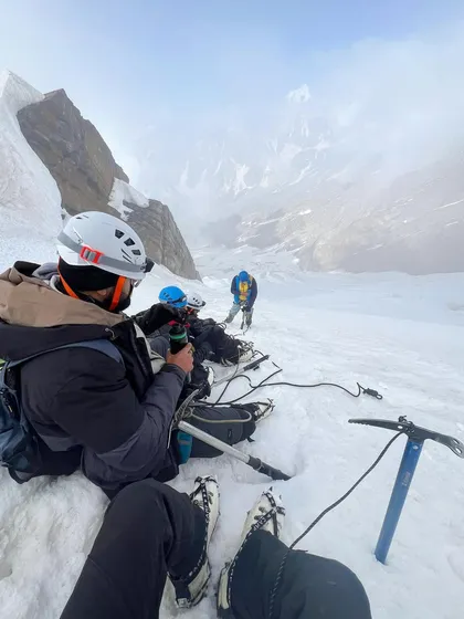 Taking a break on the snow. The Friendship Peak expedition requires proper gear like ice axes and crampons.