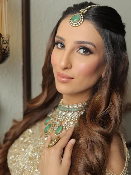 A close-up on the face, showing the flawless base and the warm, peachy tones on the cheeks and lips. The eyes are defined but not heavy.
