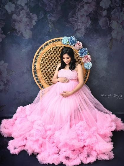 A sweet and feminine portrait. Seated in the peacock chair adorned with pink and blue flowers, the mom-to-be looks radiant in a pink tulle gown.