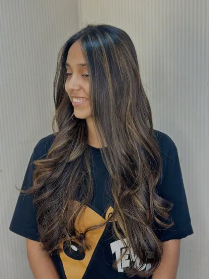 A candid shot of a client loving her new hair. The balayage highlights add brightness around her face, giving her a radiant glow.
