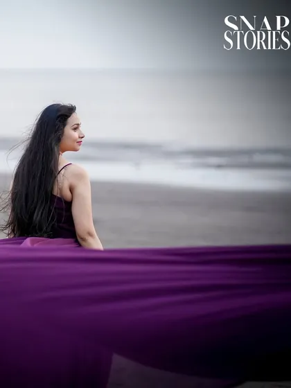 A serene and beautiful solo portrait of the bride looking out at the sea, with the flowing fabric of her dress creating a sense of movement.