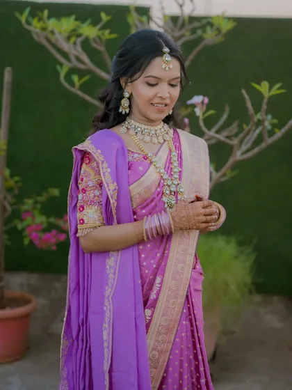 A full view of her gorgeous purple engagement saree, complemented by soft, glowing makeup and traditional Indian jewelry.