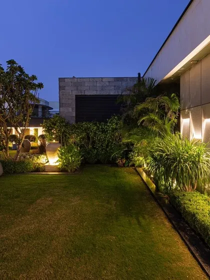 This image captures the subtle but impactful lighting along a garden wall and hedge line. The warm uplighting enhances the texture of the wall and plants, creating a soft, ambient glow that defines the garden's perimeter at night.