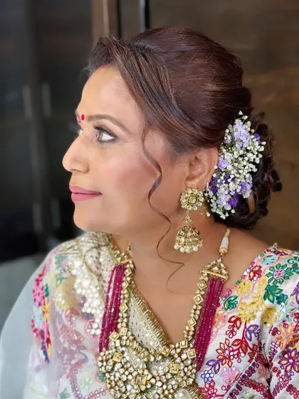 A side profile highlighting the elegant updo and the soft, glowing makeup. This is a perfect example of a timeless and graceful look for a wedding guest or family member.