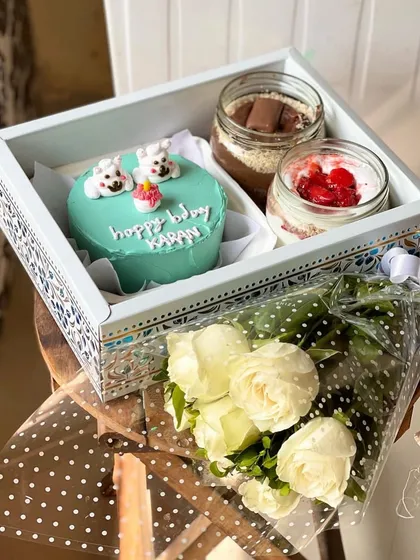 For the ultimate gift, I offer this beautiful hamper. It features a custom light blue bento cake with adorable polar bears, two delicious cake jars, and a fresh bouquet of white roses, all presented in an elegant, decorated tray.