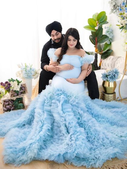 A wider shot of the couple, showcasing the magnificent train of the light blue gown. This view emphasizes the grandeur and fairy-tale quality of the maternity session.