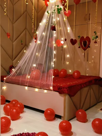 A close-up of the romantic bed canopy, decorated with fairy lights and hanging heart ornaments. The all-red theme is perfect for creating a passionate and loving atmosphere.