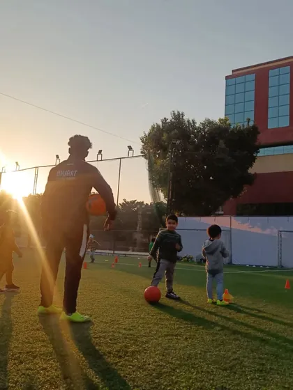 Training against a beautiful sunset. A coach demonstrates a technique to a group of young, attentive players.