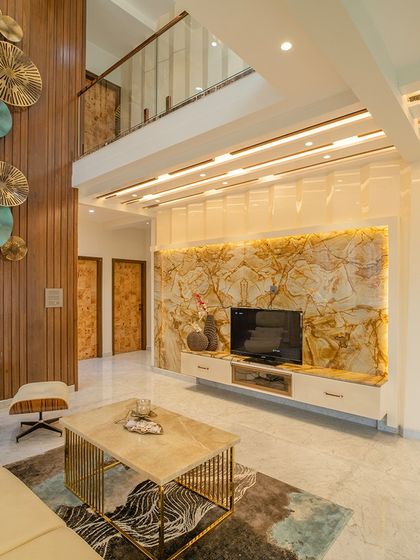 This view highlights the double-height wooden-paneled wall with a large metal art installation, adding texture and scale to the living room.