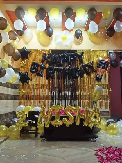 A wider view of the black and gold home decoration, showing how the balloons fill the room and create a festive party atmosphere. The rose petals on the floor add a nice touch.