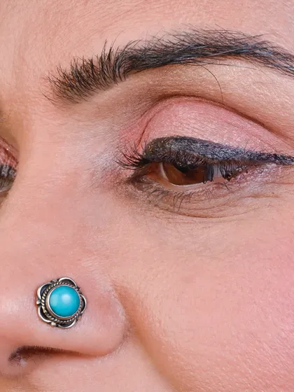 A beautiful oxidized nose pin with a turquoise stone, perfect for a traditional and bohemian look.