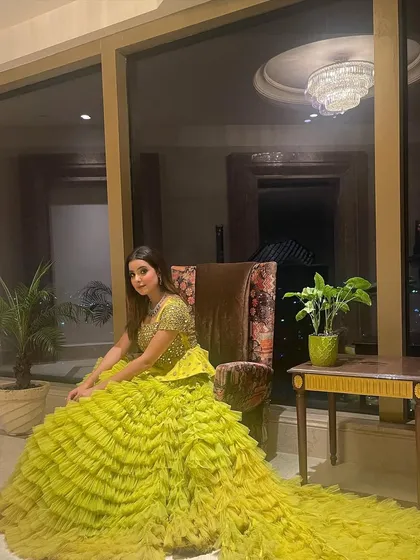 A close-up of our multilayered yellow ruffled gown with a mirror-embedded peplum top. This is a trending pick for a mehendi, combining traditional elements with a high-fashion silhouette.