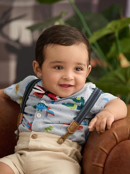 This little explorer is sitting comfortably in a leather armchair, ready for a dinosaur adventure. Themed shirts can add a fun personal touch.