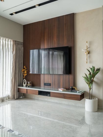 Simplicity, elevated. This media wall design is a masterclass in balance, pairing rich wooden paneling with the sleekness of glass and the polish of stone flooring. The vertical wood grain adds warmth and visual height, grounding the space.