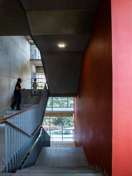 The interior of the JSW School of Public Policy at IIM Ahmedabad is defined by a clear material palette and a focus on creating interconnected spaces. This image shows the main staircase and circulation area, designed to encourage student interaction.