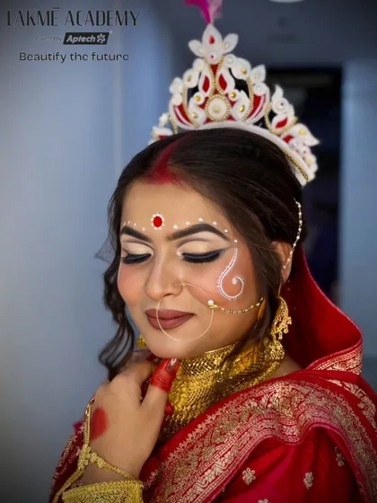 A serene close-up of a Bengali bride. The soft focus on the chandan design and the perfectly blended eyeshadow showcases the delicate artistry involved.